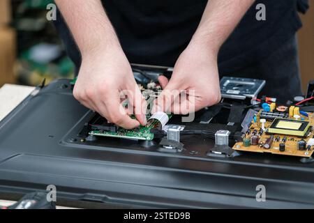 Close-up of a technician's hands repairing a TV, focusing on the intricate circuit board This image captures the precision and skill required in elect Stock Photo