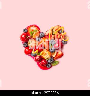 Various colorful fruits and vegetables form a heart shape, symbolizing healthy eating and love for nutritious food, set on a pink background. Stock Photo