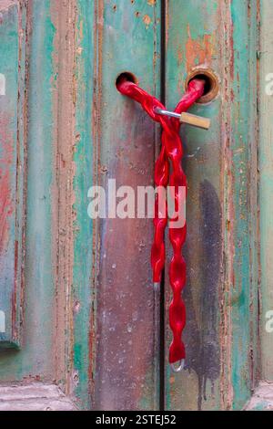 Red Chain and Padlock Securing an Old Painted Wooden Door Stock Photo