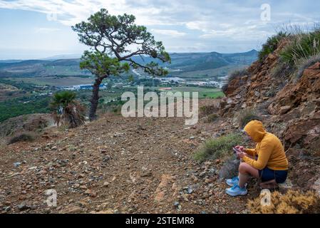 Woman sitting on a stone by the side of a mountain  road , Stock Photo