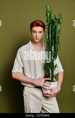 Young and handsome man stands confidently with a tall cactus, showcasing emotion and style. Stock Photo