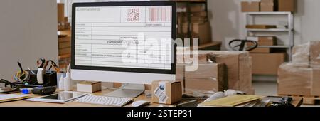 Close-up of computer monitor showing shipping label in busy office environment with various packaging materials and office supplies organized around work desk Stock Photo