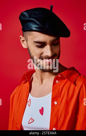 A charming young man in a heart-patterned top, orange shirt, and beret exudes style. Stock Photo