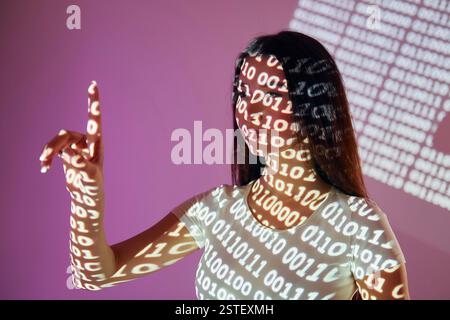 Binary machine code. Beautiful young woman is in projector neon lights in the studio. Stock Photo