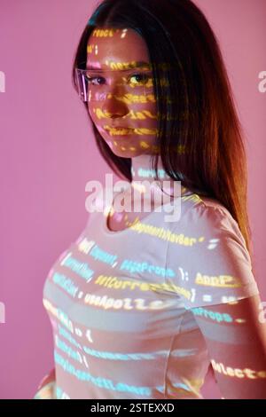 Front end programming language's scripts. Beautiful young woman is in projector neon lights in the studio. Stock Photo
