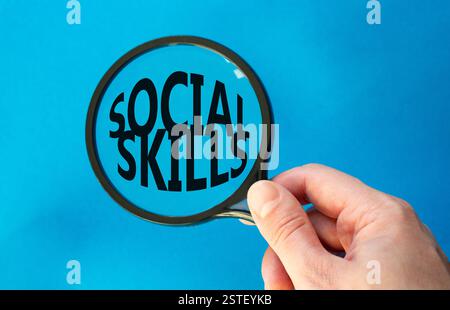 Social skills symbol. Concept words Social skills on magnifying glass. Beautiful blue background. Businessman hand. Business and Social skills concept Stock Photo