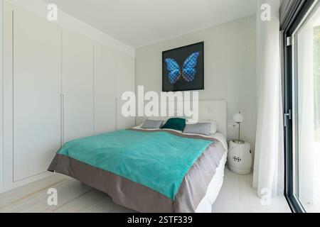 an image of a large bed with turquoise bed sheets in guest bedroom of holiday home Stock Photo
