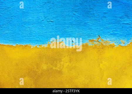 The concrete wall is half painted with blue and yellow  paint. Abstract grunge background. Bi-color concrete wall background. Ukrainian flag concept Stock Photo