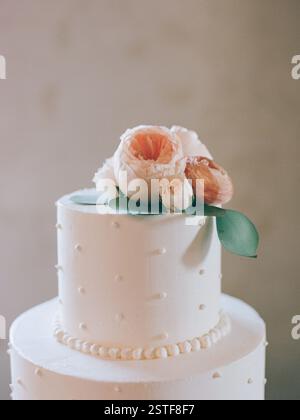 A stunning wedding cake featuring a smooth white finish and beautiful flowers on top, perfect for a special occasion. Stock Photo