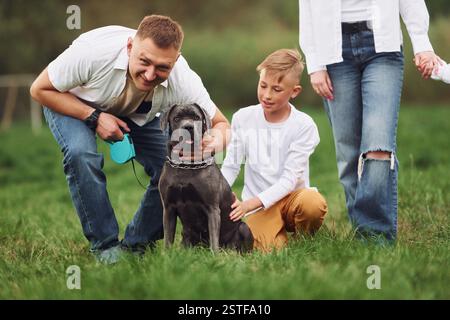 Sitting on the ground with dog. Family have weekend outdoors at summertime together. Stock Photo