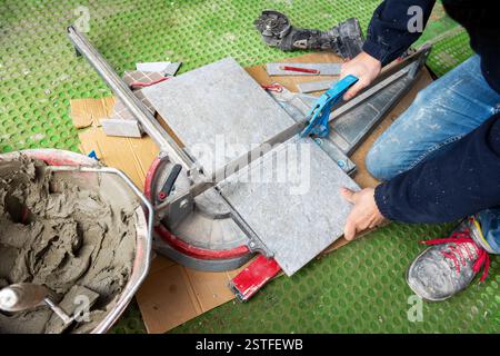 Bricklayer tiler cuts tiles to size for a new floor. Construction industry. Building. Stock Photo