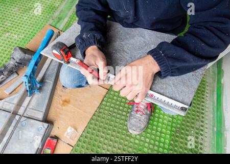 Bricklayer tiler marks cutting measurement on new floor tile. Construction industry. Building. Stock Photo