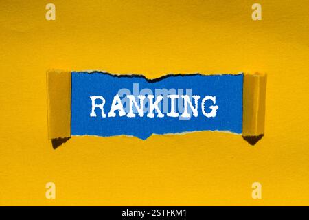 Ranking message written on ripped torn yellow paper on blue background. Conceptual ranking symbol. Copy space. Stock Photo