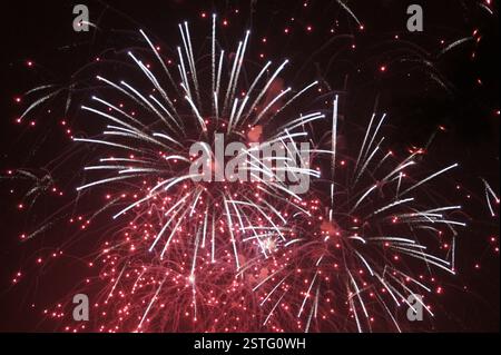 Fireworks burst in vibrant red and white streaks against a night sky. Boston. A dazzling display of celebratory light and sound. Symbolizing freedom a Stock Photo