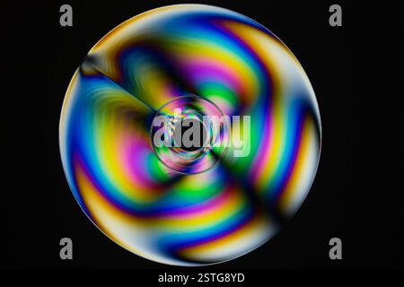 Refracted light on a CD shows the many colors of the rainbow on a black background. Stock Photo