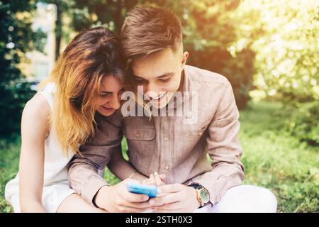 Cople using a smartphone, sitting in the park Stock Photo