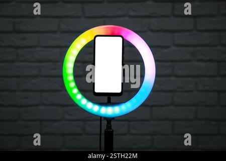 Ring lamp with smartphone against brick wall Stock Photo