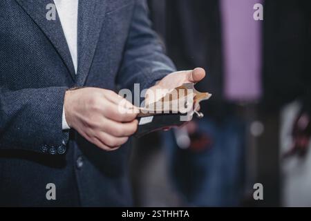 Close-up of a person in formal wear holding a detailed fabric sample for inspection Stock Photo