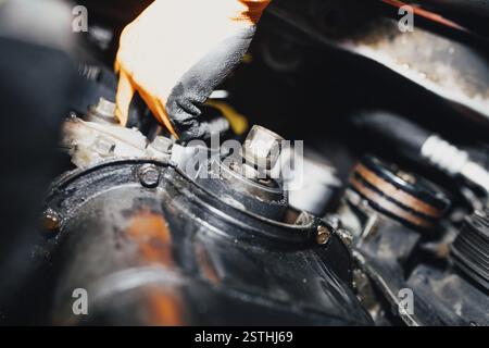 Mechanic wearing orange gloves working on engine parts with focus on tools and components Stock Photo