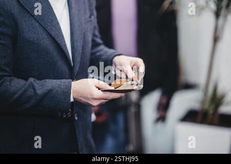 Close-up of hands in formal attire examining a fabric sample, focused on texture analysis Stock Photo