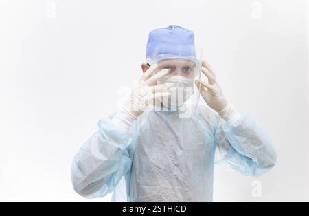 Medical professional wearing protective gear, gloves, and mask, in a clean, sterile environment Stock Photo