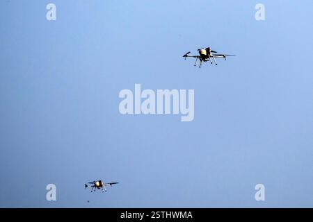 Drone is flaying against isolated blue sky / Multi-drones are flying to find information and missions Stock Photo