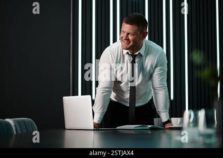 Architect looking at material samples while working on a project in office. Businessman standing at workstation in office. Medium wide shot portrait m Stock Photo