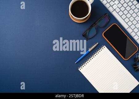 Blank touchscreen smartphone and laptop on dark blue desk Stock Photo