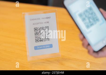Close-up of a hand holding phone and scanning qr code. Man hand paying with qr code. Selective focus on subject. Stock Photo