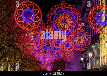 Circular, illuminated, doily style, Christmas decorations in bright pinks and purples on C. del Arenal close to Sol in Madrid, Spain. Stock Photo