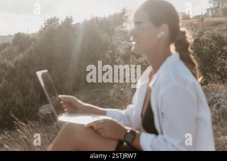 Woman Laptop Nature - A woman works on her laptop outdoors in a natural setting during the day. Stock Photo