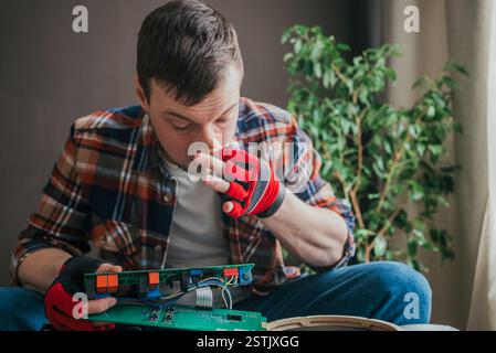 Technical professional wearing protective gloves carefully examining electronic circuit board, detecting potential overheating or malfunction through distinct burning smell Stock Photo