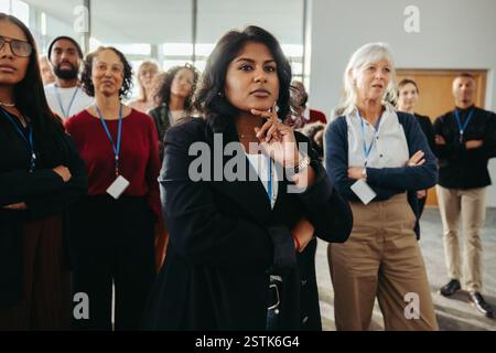 A diverse team listens intently to an engaging business speech, fostering collaboration and inspiration in a dynamic workplace setting. Stock Photo