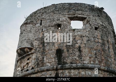 Ancient stone tower with weathered walls, a large rectangular opening, and intricate carvings. Fortress in the old town of Budva, Montenegro. Stock Photo