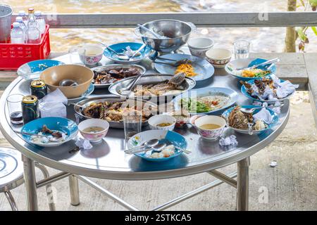 Dirty dishes with leftover food on an oval aluminum table on the porch Stock Photo