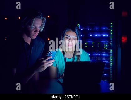 Female and male technicians using laptop in server room Stock Photo