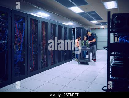 Group of technicians using laptop in server room Stock Photo