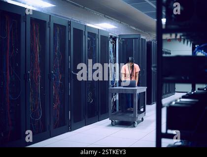 Female technician using laptop in server room Stock Photo