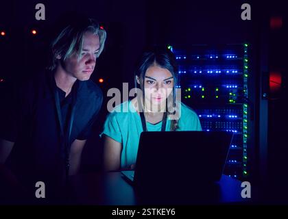 Female and male technicians using laptop in server room Stock Photo