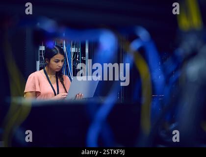 Female technician using laptop in server room Stock Photo