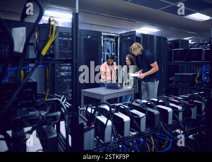 Group of technicians using laptop in server room Stock Photo
