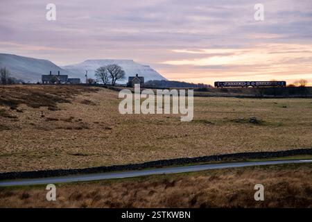 A Sprinter passenger train arrives late winter afternoon at Ribblehead Station, Yorkshire Dales National Park, on the Settle to Carlisle railway line. Stock Photo