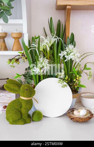 Decorative green moss bunny and blank round shape, empty circle with copy space for text and spring flowers and decorative eggs in nest. Easter holida Stock Photo