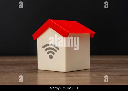 A toy house and a wifi symbol against a dark background. Home wifi, internet of things concept. Stock Photo