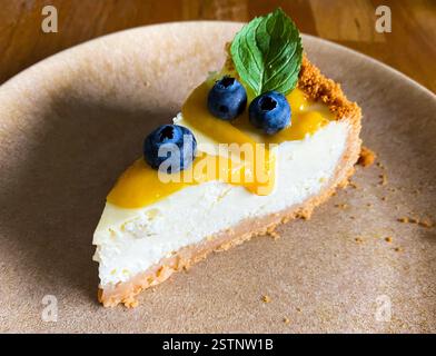 slice of cheesecake with fresh  blueberries, yellow jam and mint on the plate. side top angle  view Stock Photo