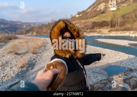 Woman in winter clothes holding hands is taking picture in front of a beautiful mountain panorama Stock Photo