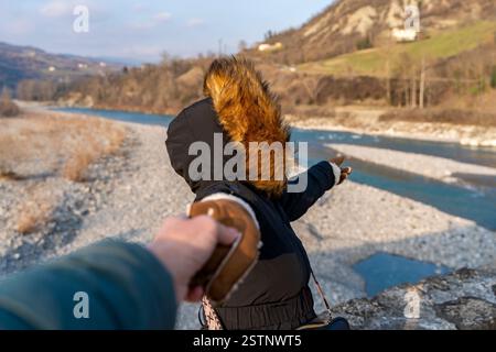 Woman in winter clothes holding hands is taking picture in front of a beautiful mountain panorama Stock Photo