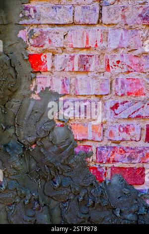 Old red brick wall half covered with cement plaster Stock Photo