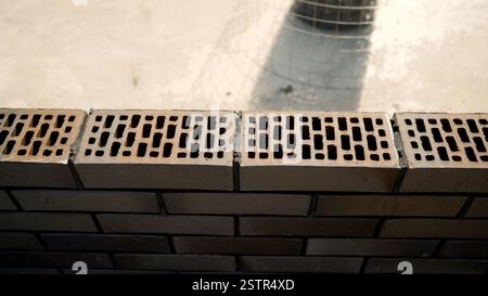 Close-up of a brick wall under construction, featuring ventilation bricks ensuring proper airflow and moisture control Stock Photo