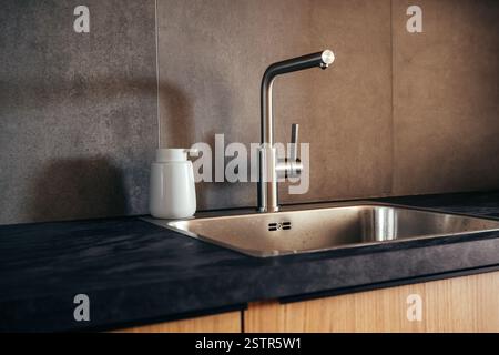 Water faucet and metallic sink in modern sleek kitchen, selective focus Stock Photo